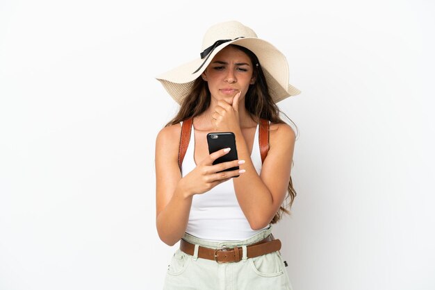 Young caucasian woman wearing a Pamela in summer holidays isolated on white background thinking and sending a message