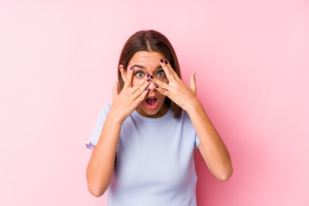 Young caucasian woman wearing a ski clothes isolated blink through fingers frightened and nervous.