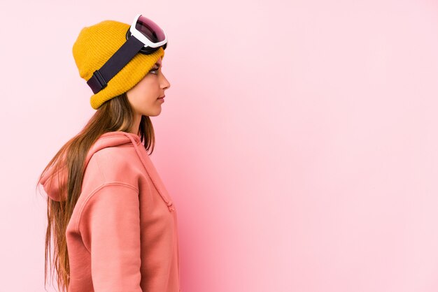 Young caucasian woman wearing a ski clothes isolated gazing\
left, sideways pose.