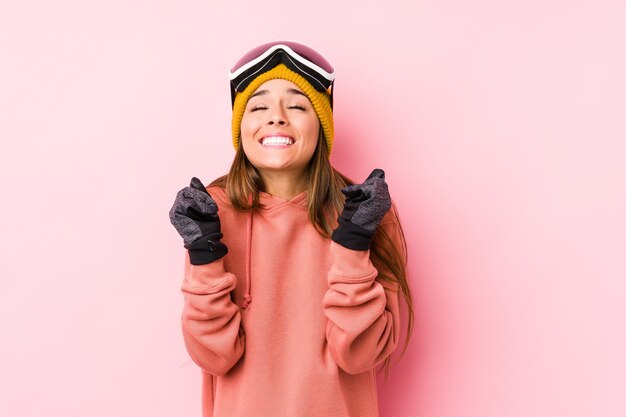 Young caucasian woman wearing a ski clothes isolated raising fist, feeling happy and successful. Victory concept.