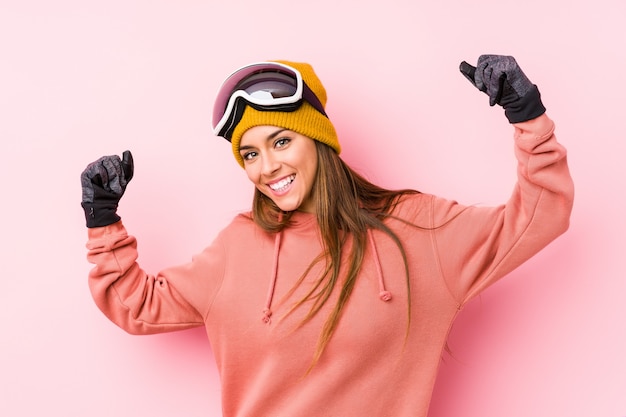 Young caucasian woman wearing a ski clothes isolated showing strength gesture with arms, symbol of feminine power