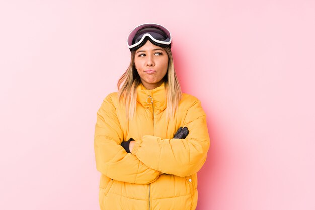 Young caucasian woman wearing a ski clothes in a pink wall frowning face in displeasure