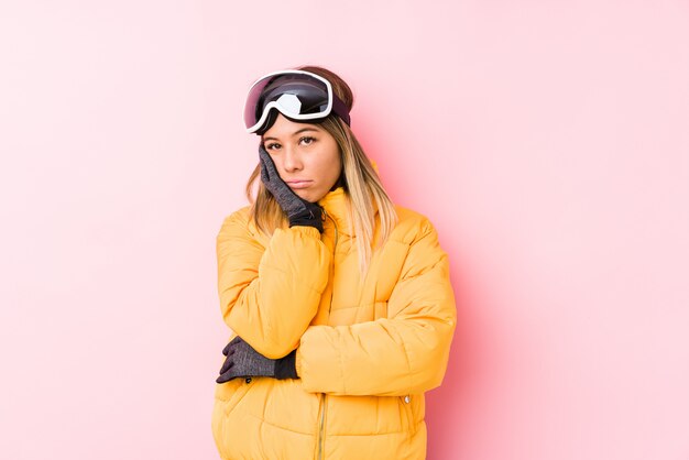 Young caucasian woman wearing a ski clothes in a pink wall who is bored, fatigued and need a relax day.