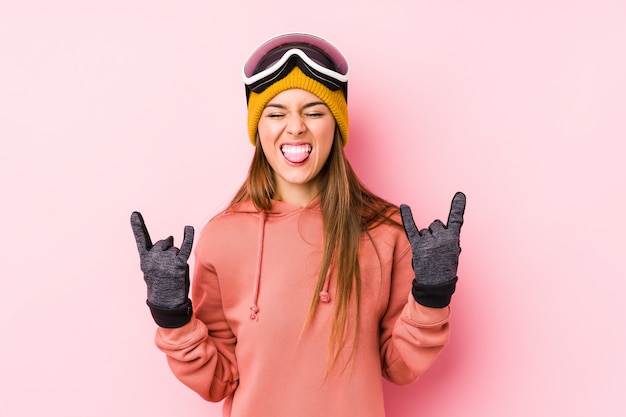 손가락으로 바위 제스처를 보여주는 스키 옷을 입고 젊은 백인 여자