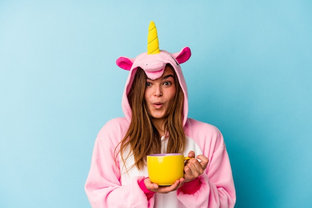 Young caucasian woman wearing an unicorn costume holding a mug isolated
