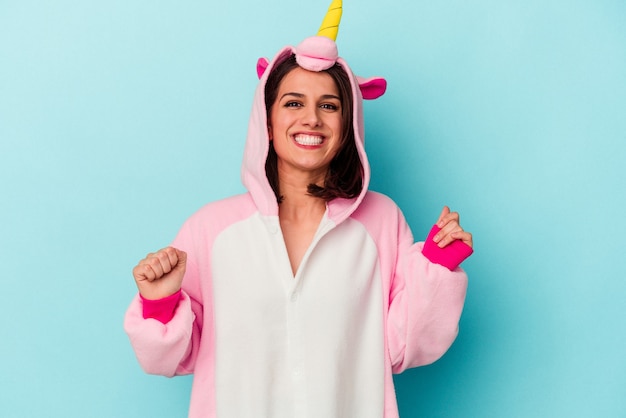 Young caucasian woman wearing an unicorn pajama isolated on blue background