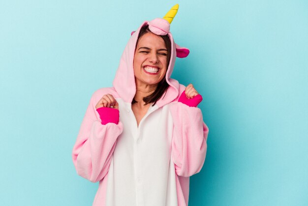 Young caucasian woman wearing an unicorn pajama isolated on blue background