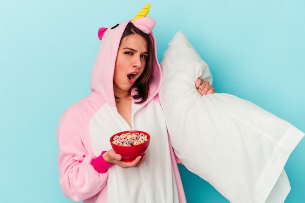 Young caucasian woman wearing an unicorn pajama isolated on blue background