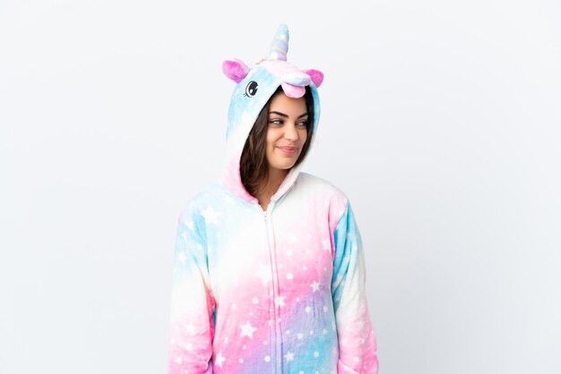 Photo young caucasian woman wearing a unicorn pajama isolated on white background looking side