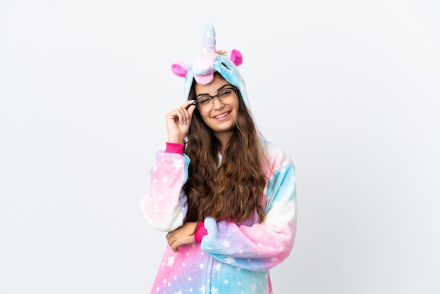 Young caucasian woman wearing a unicorn pajama isolated on white background with glasses and happy