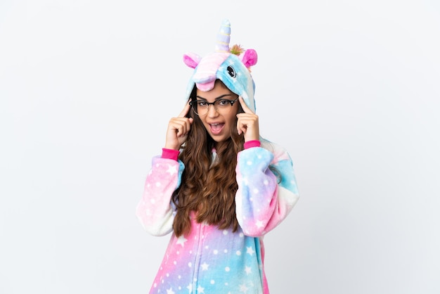 Young caucasian woman wearing a unicorn pajama isolated on white background with glasses and surprised