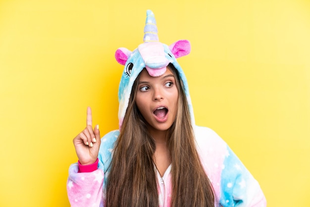 Young caucasian woman wearing a unicorn pajama isolated on yellow background thinking an idea pointing the finger up