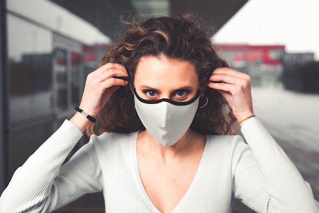 Young caucasian woman wearing a white mask at the street