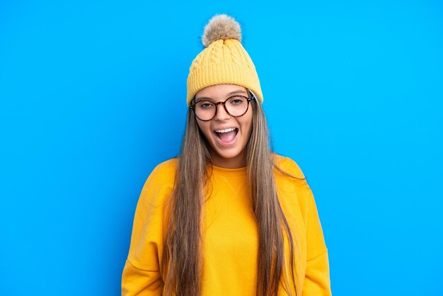 Young caucasian woman wearing winter clothes isolated on blue background with surprise facial expression