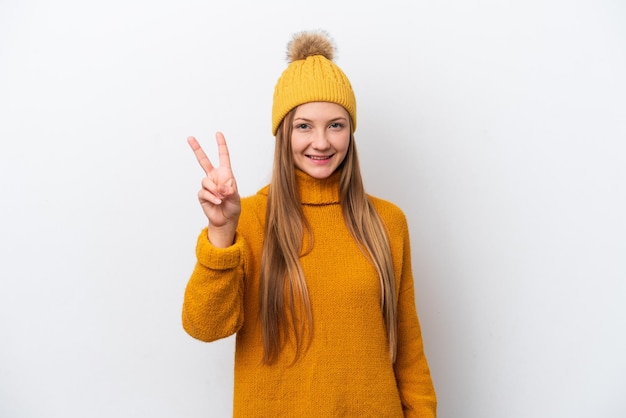 Young caucasian woman wearing winter jacket isolated on white background smiling and showing victory sign