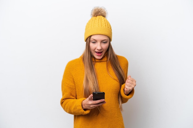 Young caucasian woman wearing winter jacket isolated on white background surprised and sending a message