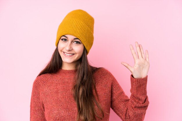 Young caucasian woman wearing a wool cap smiling cheerful showing number five with fingers.