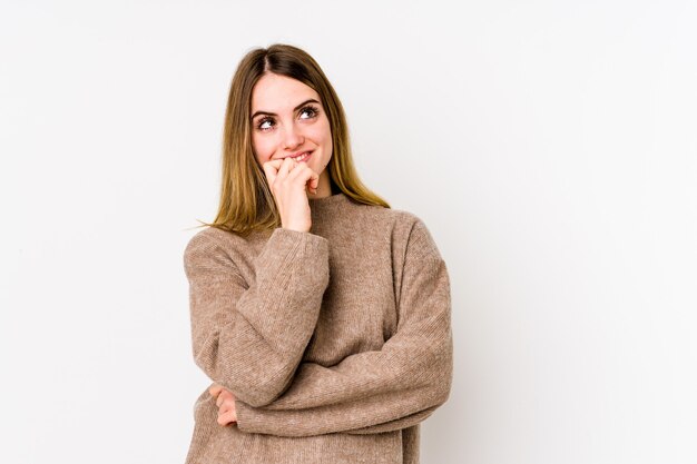 Young caucasian woman on white relaxed thinking about something looking at a copy space.