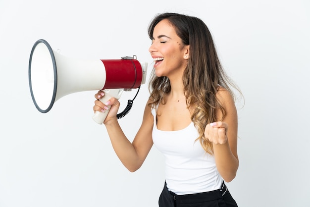 Young caucasian woman on white shouting through a megaphone to announce something in lateral position