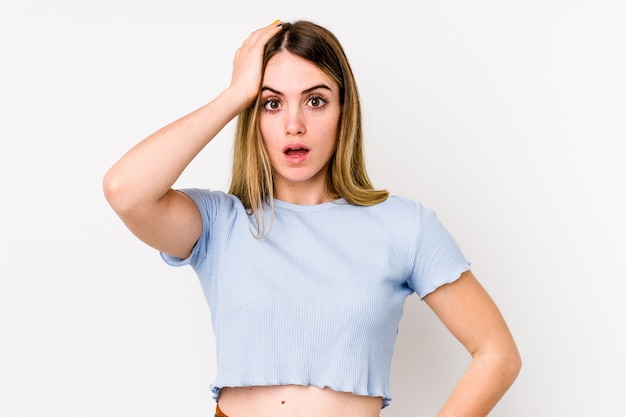 Young caucasian woman on white wall being shocked