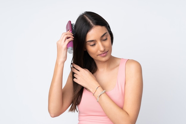 Young caucasian woman on white wall with hair comb