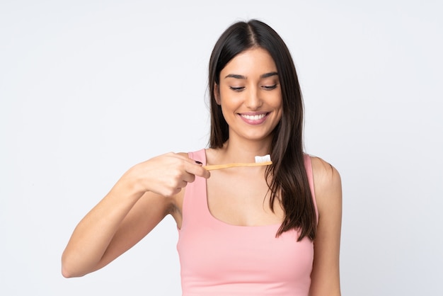 Young caucasian woman on white wall with a toothbrush