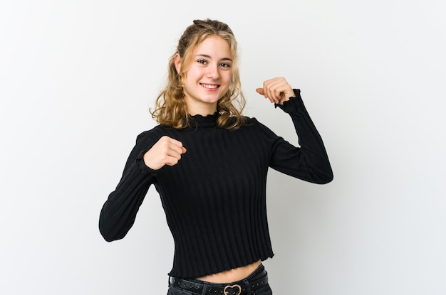 Young caucasian woman on white wallcelebrating a special day, jumps and raise arms with energy.