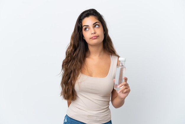 Young caucasian woman with a bottle of water isolated on white background and looking up