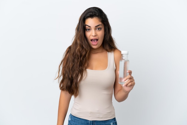 Young caucasian woman with a bottle of water isolated on white background with surprise facial expression