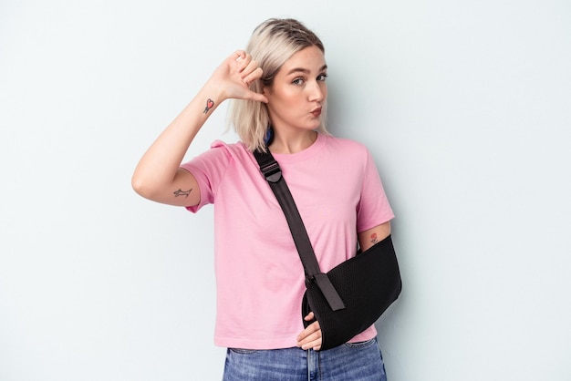 Photo young caucasian woman with broken hand isolated on blue background feels proud and self confident, example to follow.