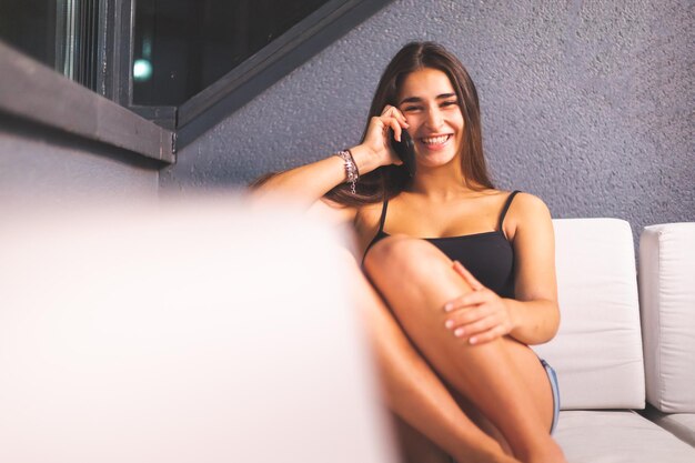 Young caucasian woman with a cell phone at terrace sofa at night. Madrid, Spain.