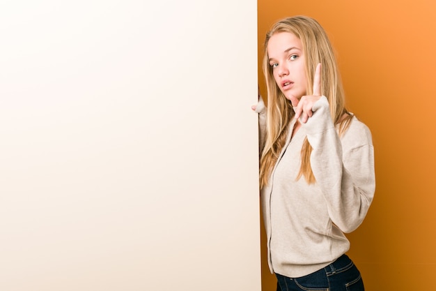 Young caucasian woman with copy space showing number one with finger.