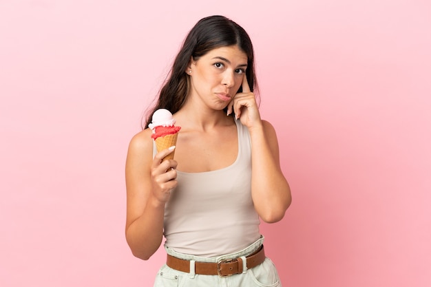 Young caucasian woman with a cornet ice cream isolated on pink background thinking an idea