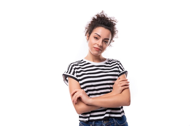 Photo young caucasian woman with a curly haircut dressed in a striped summer tshirt looks thoughtfully to