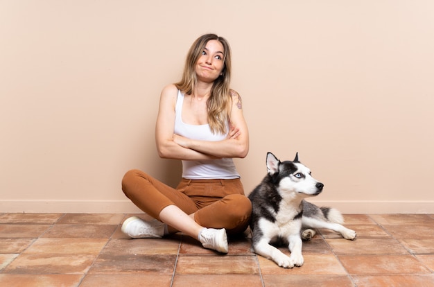 Giovane donna caucasica con il cane sopra la parete isolata