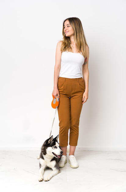 Young caucasian woman with dog over isolated wall