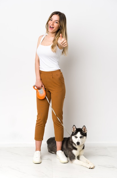 Young caucasian woman with dog over isolated wall