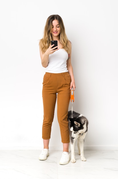 Young caucasian woman with dog over isolated wall