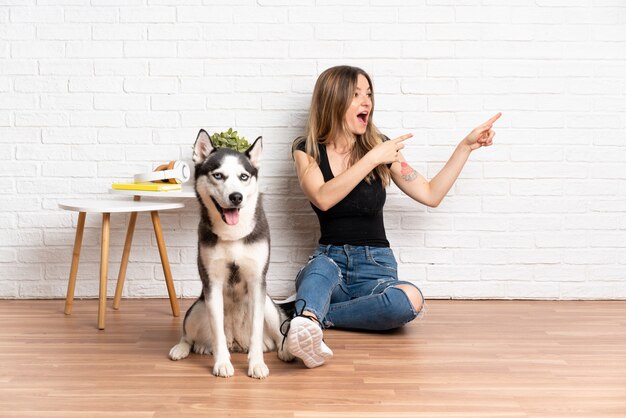 孤立した壁の上の犬を持つ若い白人女性