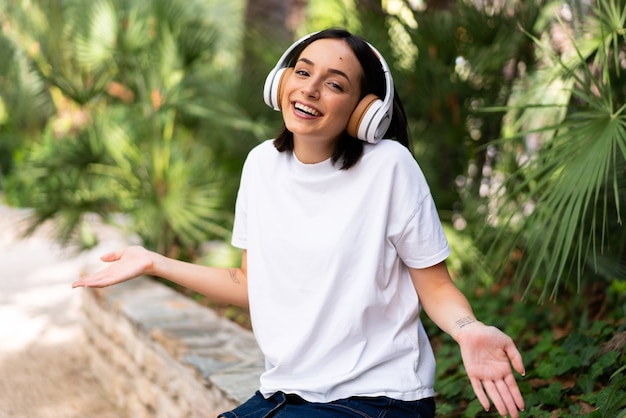 Giovane donna caucasica con le cuffie a sorridere all'aperto