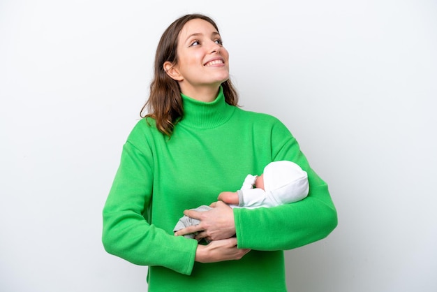 Young caucasian woman with her cute baby isolated on white background looking up while smiling