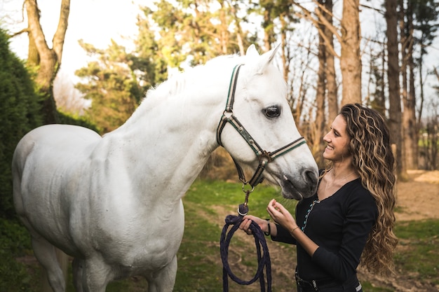 Young caucasian woman with a horse in a equestrian centre