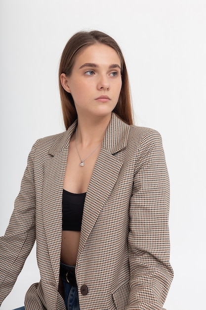 Young caucasian woman with long brown hair in suit jacket on white background