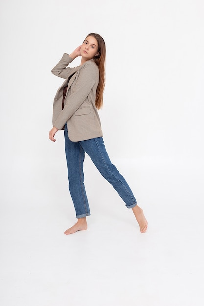 Young caucasian woman with long brown hair in suit jacket on white background