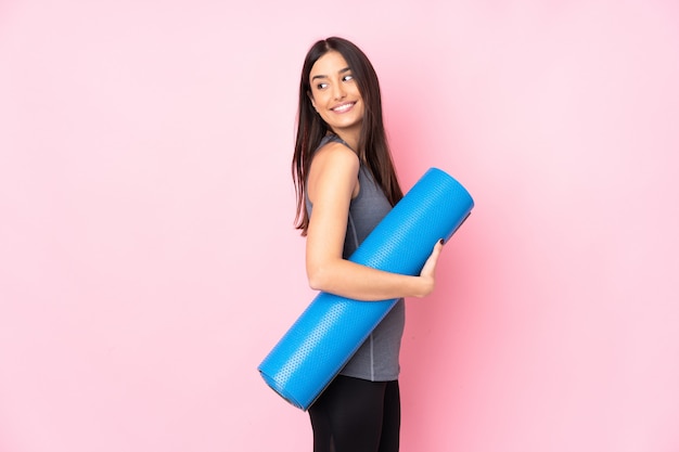 Young caucasian woman with mat on pink wall laughing