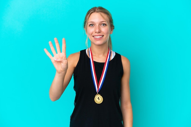파란색 배경에 격리된 메달을 가진 젊은 백인 여성은 행복하고 손가락으로 4를 세고 있습니다.