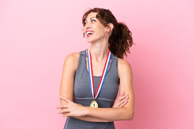 幸せと笑顔のピンクの背景に分離されたメダルを持つ若い白人女性