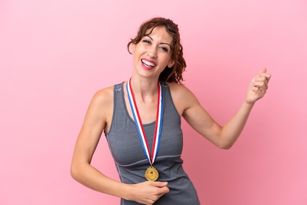 Young caucasian woman with medals isolated on pink background making guitar gesture