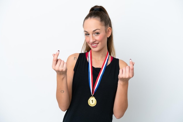 Young caucasian woman with medals isolated on white background making money gesture