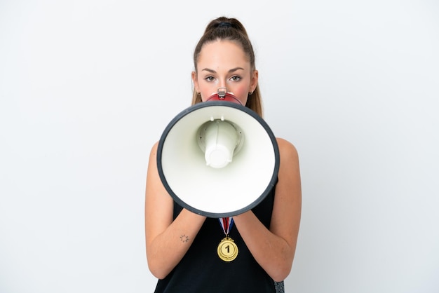 Молодая кавказская женщина с медалями на белом фоне кричит в мегафон